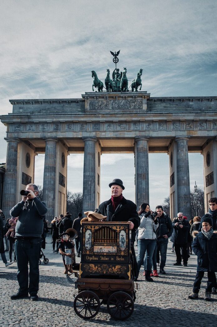 Street performer at Berlin's iconic Brandenburg Gate, engaging the crowd with a unique musical instrument.